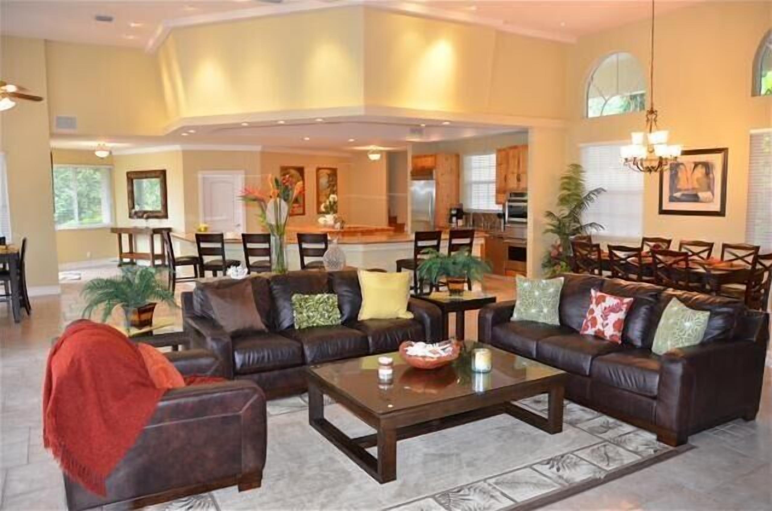 A spacious living area with leather sofas, a coffee table, and a dining area with chairs and a table.