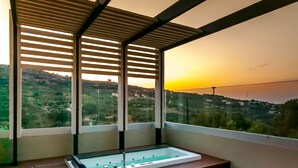 Ein modernes Zimmer mit Blick auf einen Sonnenuntergang über einer hügeligen Landschaft.
