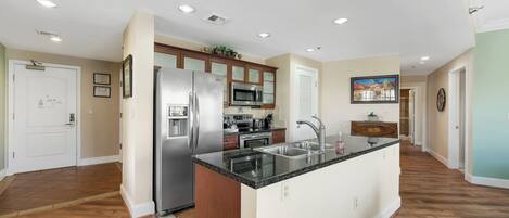 A modern kitchen with a central island, stainless steel appliances, and wooden cabinetry.