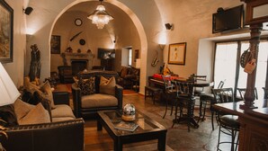 A cozy living room with a fireplace, comfortable seating, and a piano. - Meson Real de la Plata (El Marques)