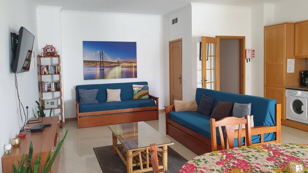 A living room with a sofa, a coffee table, a TV, a bookshelf, and a painting of a bridge.
