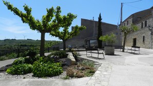 Un patio con bancos de piedra, un árbol y un edificio de paredes de piedra.