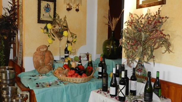 Comedor con una mesa dispuesta para una comida, que presenta una variedad de frutas, verduras y botellas de vino.