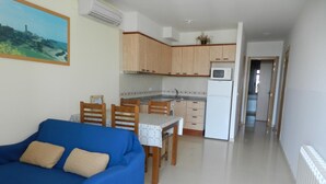 Un espacio habitable compacto con kitchenette, comedor y sofá.