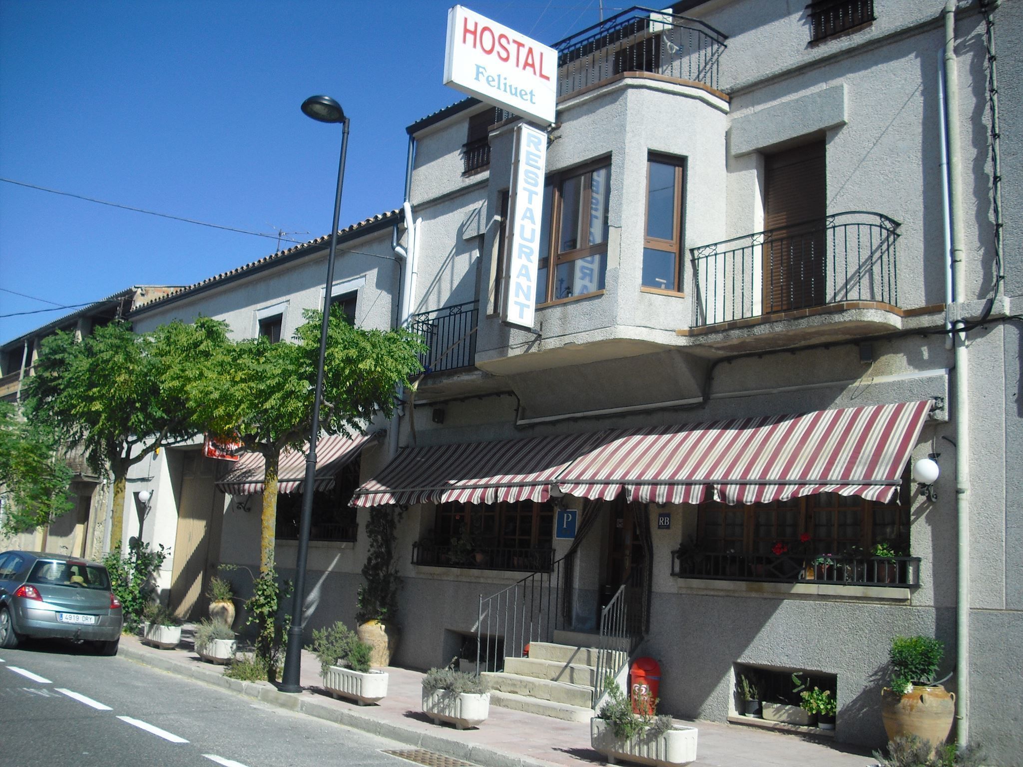 A building with a sign reading "HOSTAL Feliziet" and a striped awning.