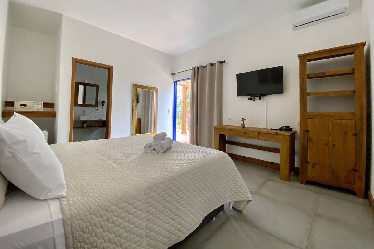 A bedroom with a bed, a desk, a television, and a wardrobe.