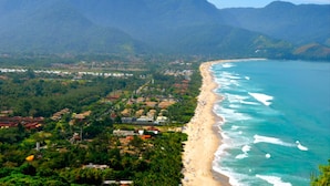A coastal town with a beach, houses, and mountains in the background. - Porto Grande Hotel & Convention (São Sebastião)