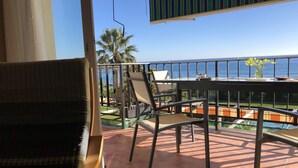 Ein Balkon mit Tisch und Stühlen, der einen Blick auf ein Schwimmbad und Palmen bietet.