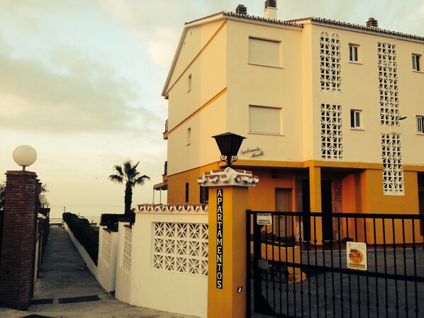 Un edificio con una entrada portonada, un letrero que dice "APARTAMENTOS" y un farol.