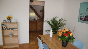 A dining area with a wooden table, blue chairs, a vase of flowers, and a bookshelf. - Chickes apartment in perfect location (Graz)