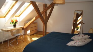 A room with a sloped ceiling, skylight windows, a desk with a chair, a bed with pillows, and a mirror. - Chickes apartment in perfect location (Graz)