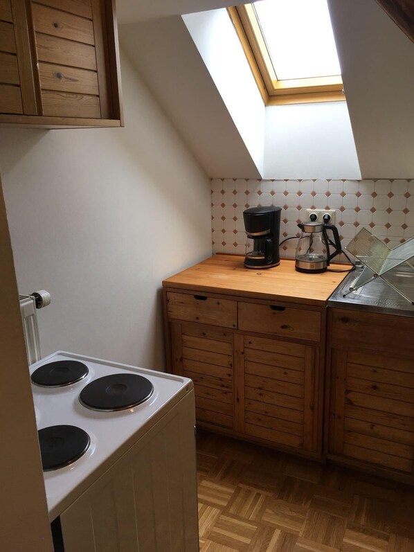 Une petite cuisine avec un puits de lumière, des placards en bois, une cuisinière et une machine à café.