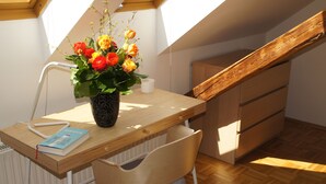 A small, well-lit attic room with a wooden desk, a chair, and a vase of flowers. - Chickes apartment in perfect location (Graz)