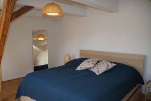 A bedroom with a wooden headboard, a blue bedspread, two patterned pillows, a woven light fixture, and a mirror on the wall. - Chickes apartment in perfect location (Graz)