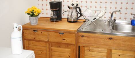 A kitchen with wooden cabinets, a coffee maker, a kettle, and a sink.