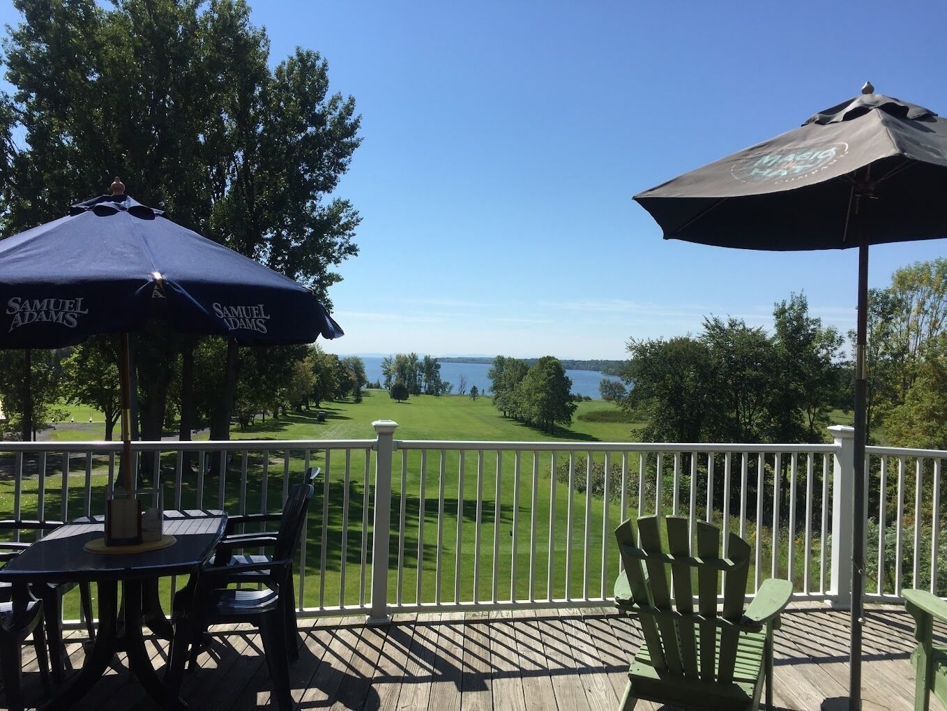 Une terrasse avec des sièges extérieurs, une vue sur un terrain de golf et un plan d’eau visible au loin.