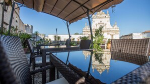 An outdoor seating area with wicker furniture and a glass table reflecting a building. - Castello Castriota Scanderbeg Suites De Charme (Galatina)