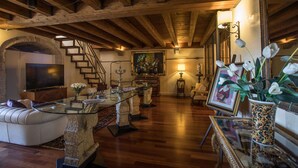 A spacious living room with a stone fireplace, a glass coffee table, a white sofa, and a wooden staircase. - Castello Castriota Scanderbeg Suites De Charme (Galatina)