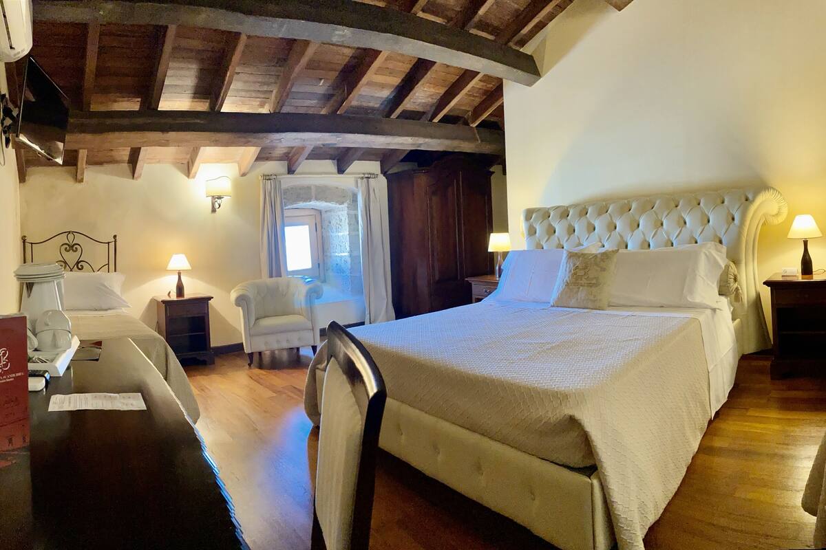 Une chambre d’hôtel avec un grand lit, une chaise, un bureau et une petite table avec une lampe.