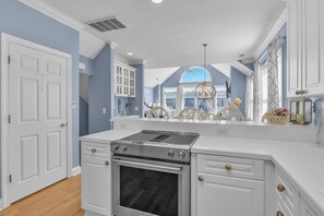 A kitchen with a stainless steel stove, white cabinetry, and a large window.