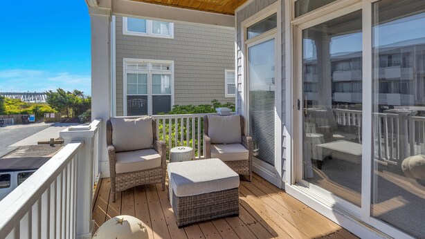 A covered porch with wicker furniture, a small round table, and a sliding glass door leading to a balcony.