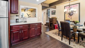 A modern kitchen with dark wood cabinets, a white countertop, and a dining area with a glass table and dark chairs.