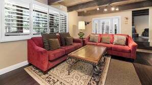 A living room with two red sofas, a wooden coffee table, and patterned rugs.