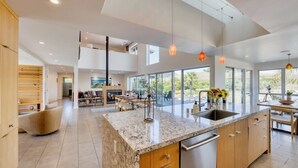 A modern kitchen with a large island, wooden cabinets, and a stainless steel dishwasher. - Private Sonoma Vineyard Estate: Modern Villa + Pool 10 Acre Winery Property (Sonoma)