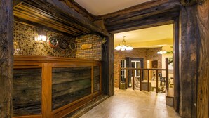 A reception area with a wooden reception desk, a tiled wall with clocks, and a chandelier. - The Forest and lake by Schofieldshire (Nuwara Eliya)