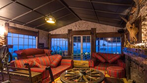 A cozy room with a large window, a wooden table, and red patterned sofas. - The Forest and lake by Schofieldshire (Nuwara Eliya)