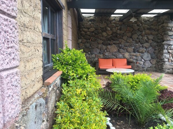 A stone wall, a window, and a seating area with a cushion and a table. - Rancho Escondido Casa Goyri (Tlaxco)