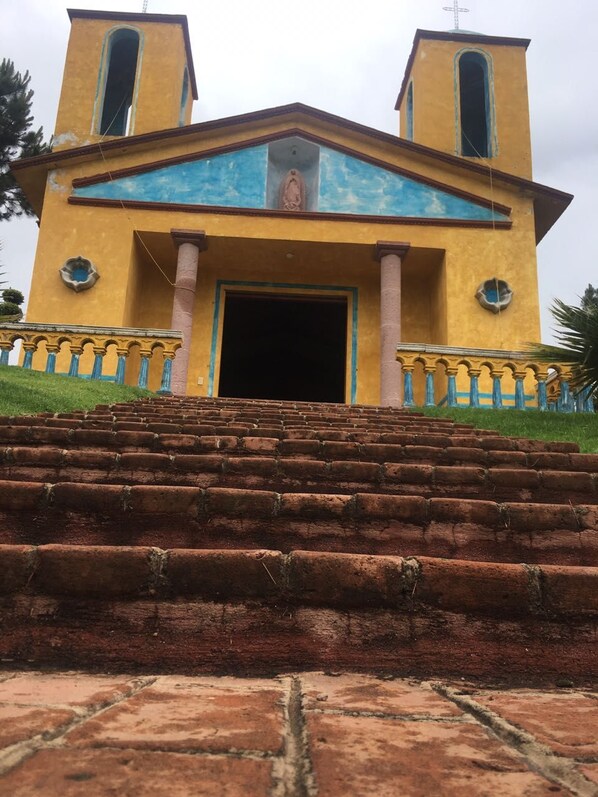 A church with a central entrance, two bell towers, and a staircase leading up to the entrance. - Rancho Escondido Casa Goyri (Tlaxco)
