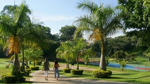 A pathway lined with palm trees and well-maintained bushes, leading to a sports field. - Hotel Fazenda Reviver (Araçoiaba da Serra)