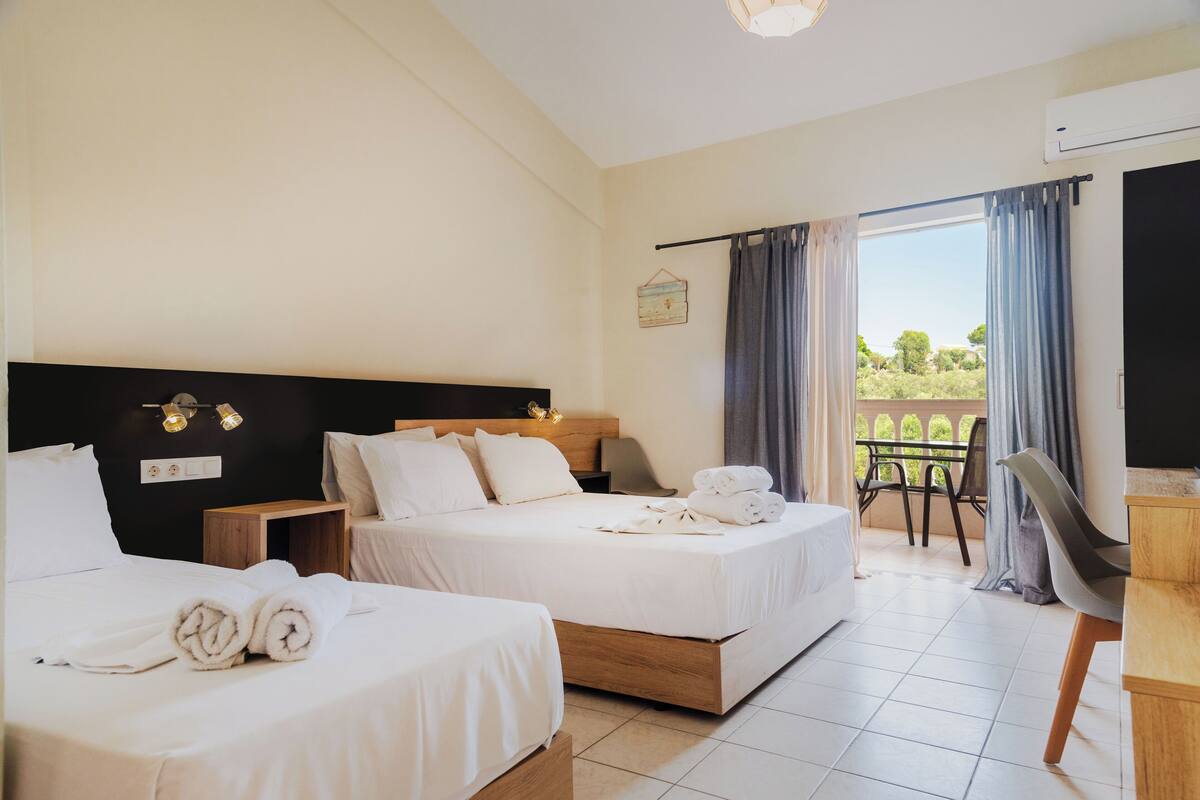 Une chambre d’hôtel avec deux lits, un bureau et un balcon offrant une vue.