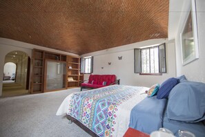 A bedroom with a brick ceiling, a bed with a colorful quilt, a red chair, and a wardrobe. - Casa Ayvar (Mexico City)