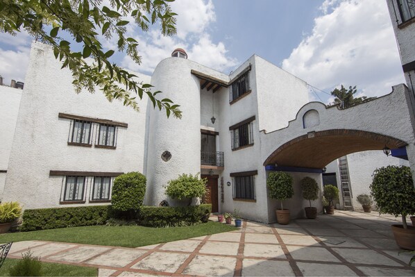 A white building with multiple windows and a covered patio area. - Casa Ayvar (Mexico City)