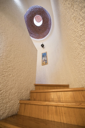 Eine Holztreppe führt zu einem runden Dachfenster.