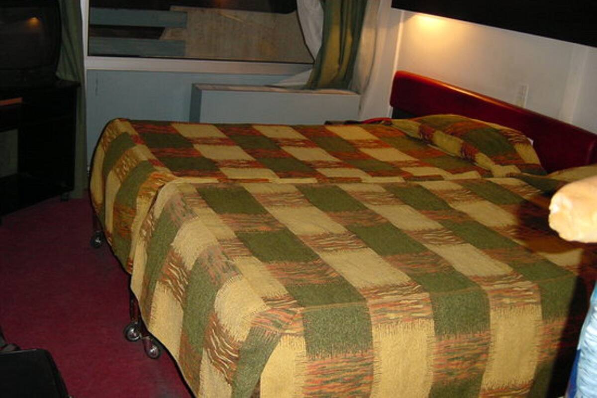 A hotel room with a bed, a desk, and a window with curtains.