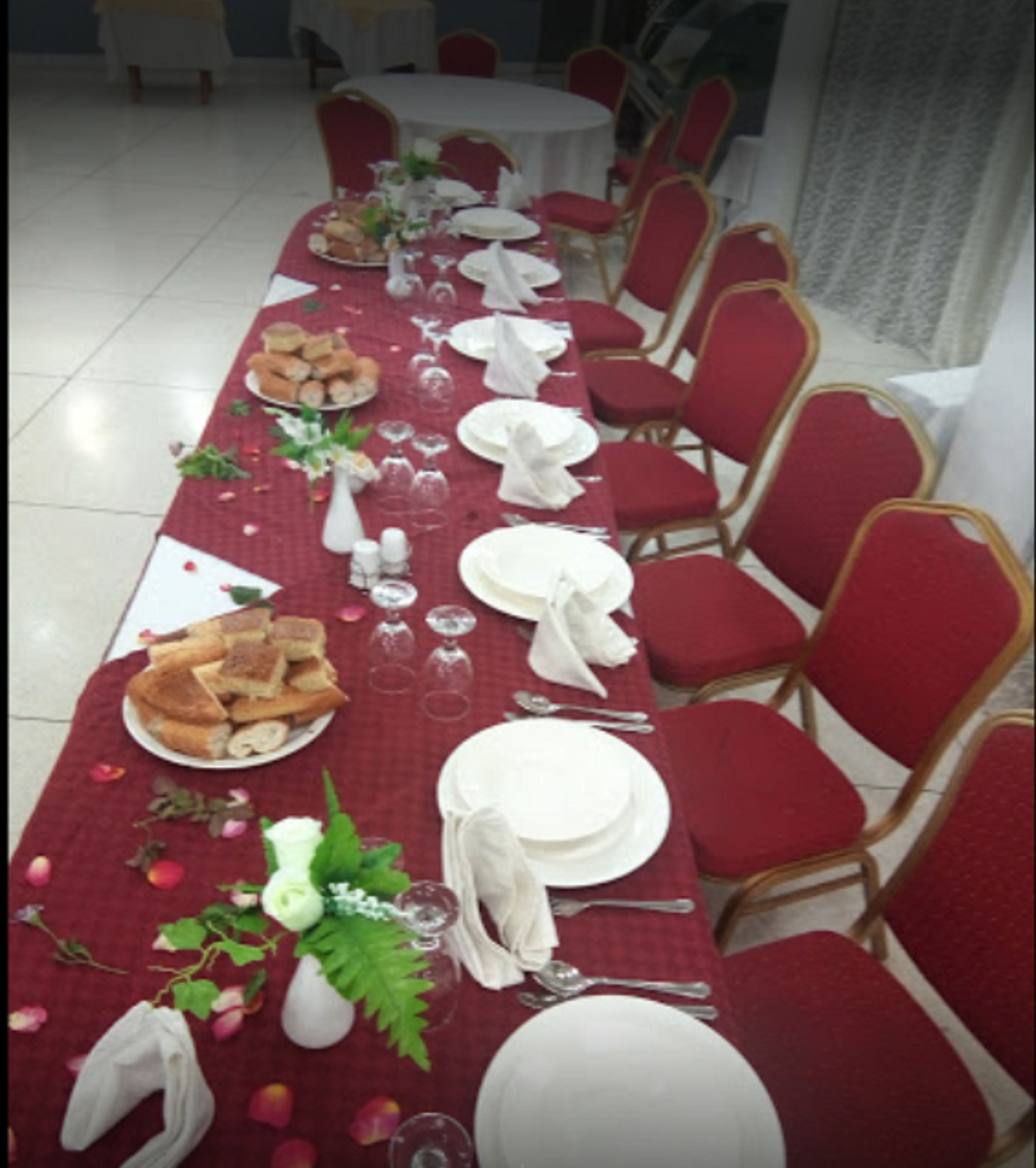 Una larga mesa de comedor dispuesta con platos, vasos y un centro de mesa.
