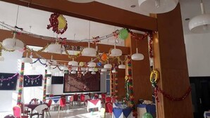 Ein Raum mit mehreren Tischen und Stühlen, festlich geschmückt mit Girlanden und Luftballons.