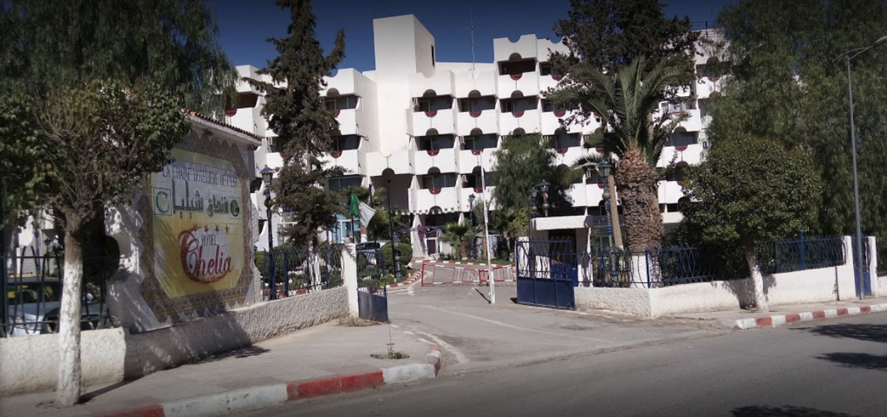 A hotel with a modern architectural design, featuring a series of balconies and a prominent entrance gate.