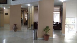 Eine geräumige Lobby mit Fliesenboden, einem Blumentopf, einer Vase und einer Treppe zu den oberen Etagen.