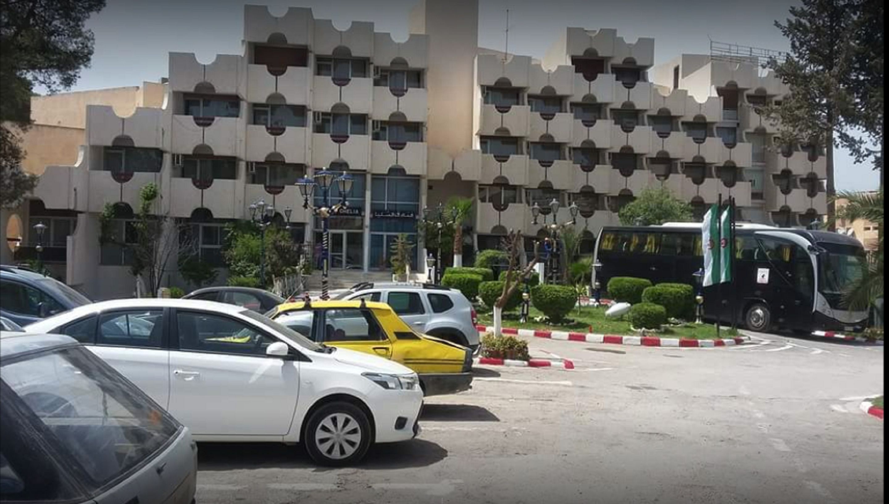 Un estacionamiento con varios autos, un autobús y un edificio de diseño arquitectónico singular.