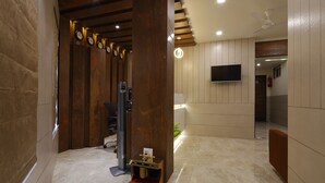 Un hall d’hôtel moderne avec un comptoir d’accueil en bois, un grand téléviseur à écran plat et un ventilateur de plafond.
