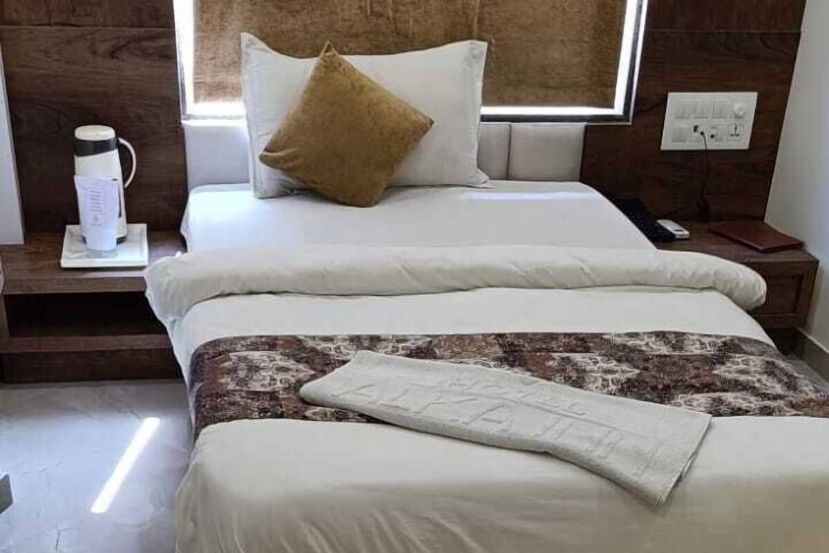 A hotel room with a large bed, a nightstand, a bedside table, and a window with curtains.