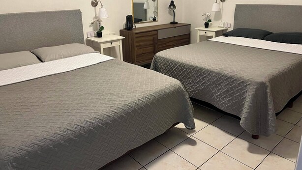 A hotel room with two beds, a dresser, a mirror, and bedside lamps. - Brisas del Caribe Suite (Playa del Carmen)