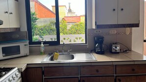 A kitchen with a window, a microwave, a sink, a coffee maker, and a toaster. - Brisas del Caribe Suite (Playa del Carmen)