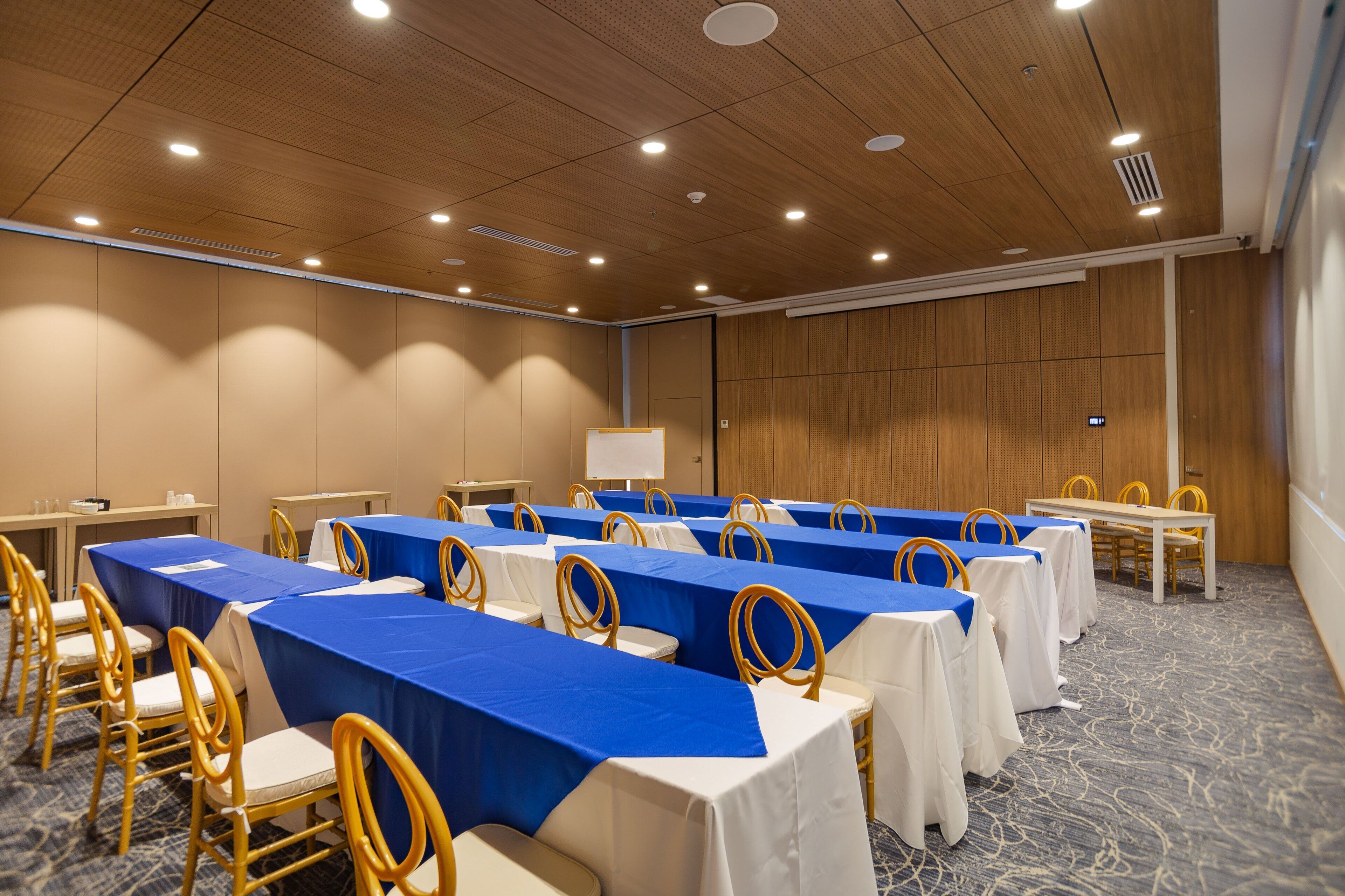 A conference room with tables and chairs, a whiteboard, and a carpeted floor.