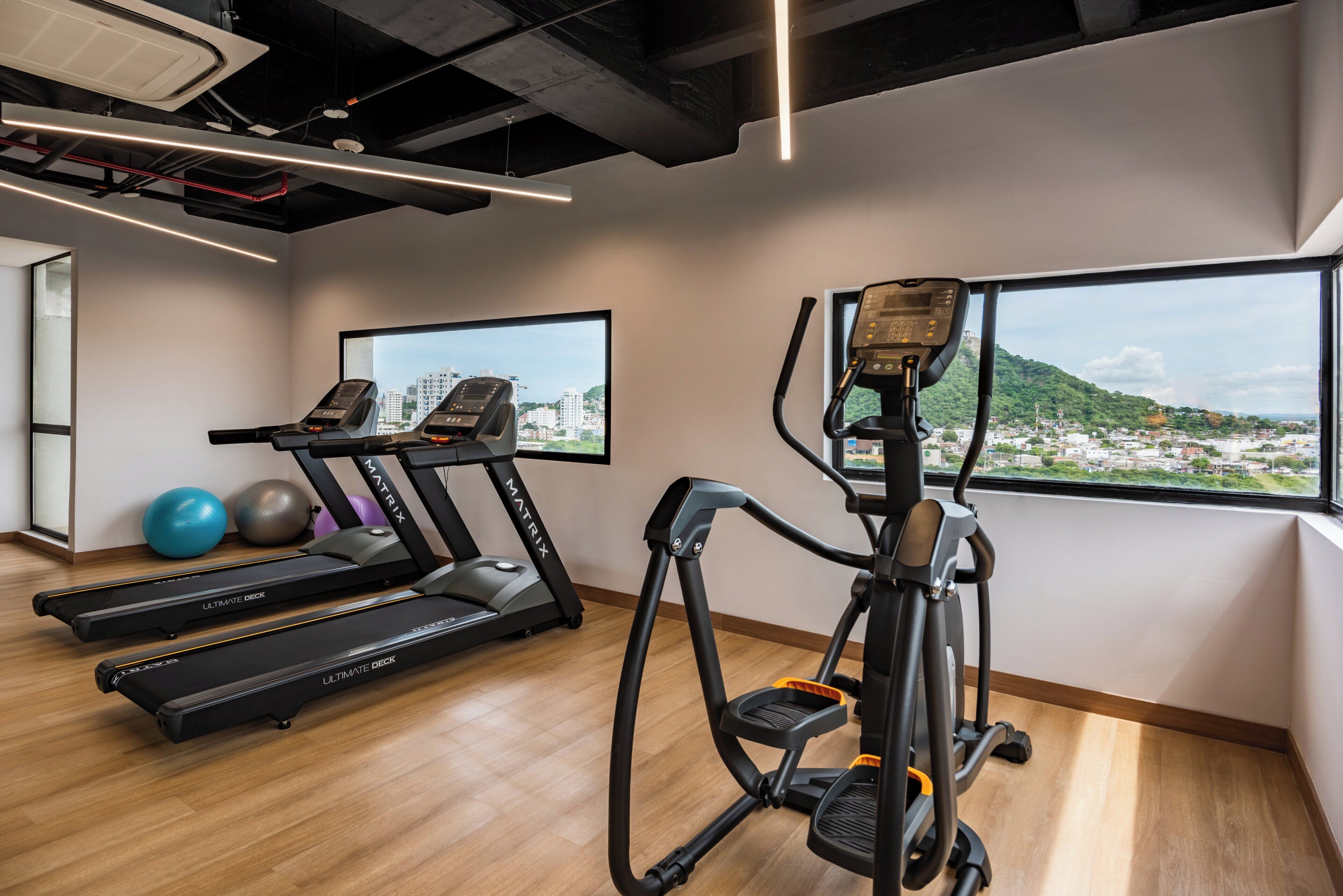 Un gimnasio con cintas de correr, elípticas y pelotas de ejercicio.