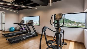 Un gimnasio con cintas de correr, elípticas y pelotas de ejercicio.